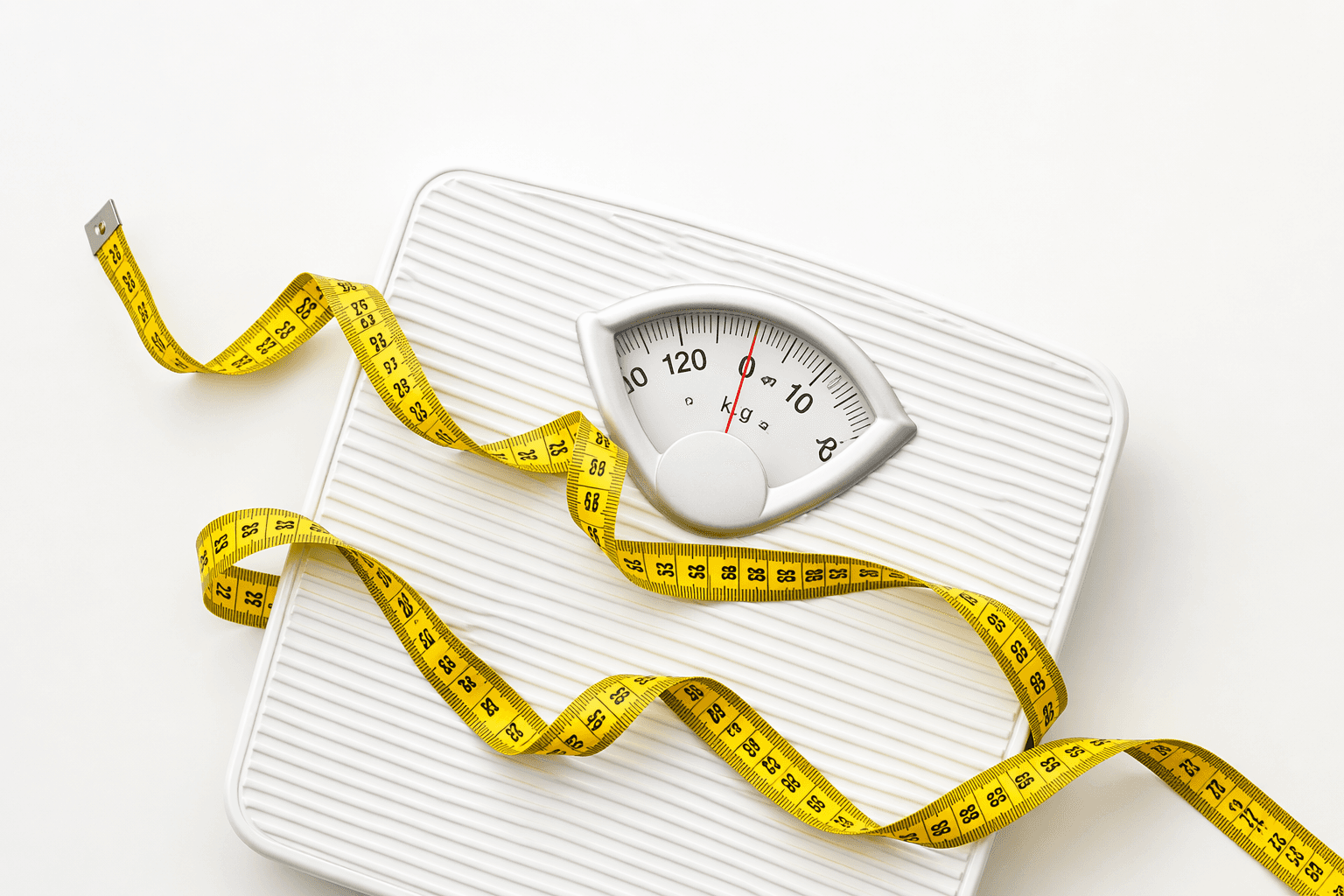 White analog bathroom scale with a yellow measuring tape draped over it on white background.